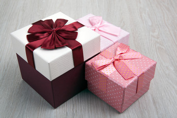 three colored gift boxes with bows on a gray wooden background