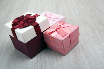 three colored gift boxes with bows on a gray wooden background