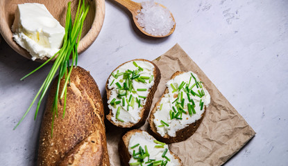 Small pieces of bread with curd spread decorated by green fresh chive background flat lay