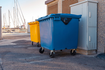 Garbage containers. Blue and yellow recycling containers.	