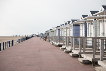Obraz premium brighton, england, 05/05/2018 Beautiful retro vintage wooden seaside huts on a promenade on the coast. Sunny beach traditional holidays with a neutral pastel colour. Wooden seaside buildings.