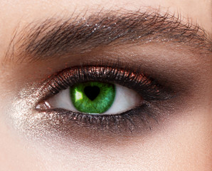 A female eye close up with a pupil in the form of heart. A card by St. Valentine's Day.