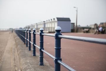 A rustic metal seaside bannister railing against a sandy beach backdrop. railings saves lives at the seaside. vintage seaside architecture.