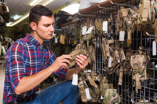 Man choosing holster for gun in military shop
