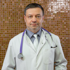 Close up a doctor with stethoscope around his neck looking at the camera