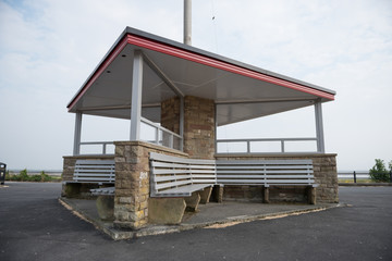 A beautiful wooden retro british seaside shelter on the promenade. unusual architecture, red and grey colour painted seats and trimming. shelter at the beach.