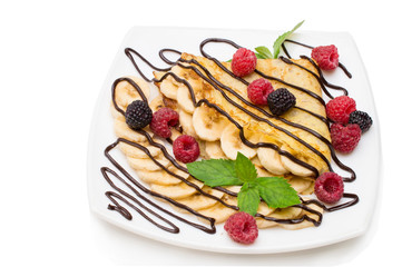 homemade crepes with chocolate cream, banana and blueberries on white background. pancakes