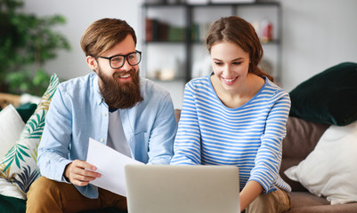 married couple with bills receipts documents and laptop at home