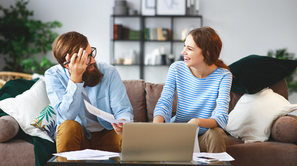 married couple with bills receipts documents and laptop at home