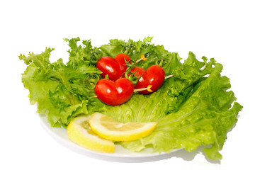 three small red tomato cherry on the green iceberg salad and lemon slidce