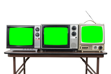 Three vintage televisions on wood table isolated on white with chroma key green screens.