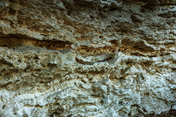 Picturesque background of collapsing surface of limestone rock. Abstract beautiful forms of weathering stone rocks, huge cracks and washed cavitie in stone, danger of collapse and landslide earthquake