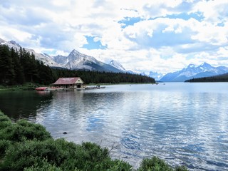 Maligne lake in Jasper national park, with calm and still waters and a handful of rowboats for tourists to rent on a quiet July summer day.