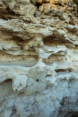 Picturesque background of collapsing surface of limestone rock. Abstract beautiful forms of weathering stone rocks, huge cracks and washed cavitie in stone, danger of collapse and landslide earthquake