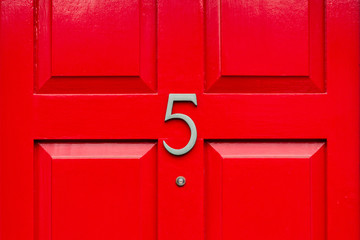 House door number five as a bronze number on a red wooden house door