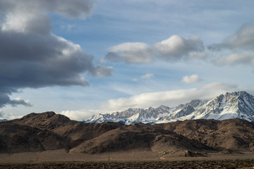 Naklejka na ściany i meble snowy mountains brown desert hills clouds sky Eastern Sierras of California winter landscape