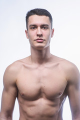 Fototapeta premium Beautiful young European athletic with bare torso, nice abs and muscles on white and gray background