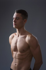 Beautiful young European athletic with bare torso, nice abs and muscles on white and gray background