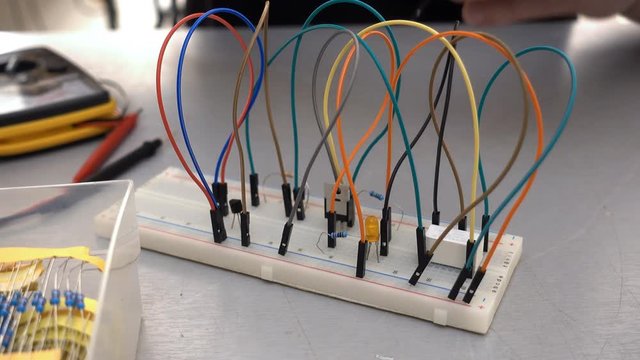 Maker, student or electronics engineer developing prototype electronics circuit on breadboard