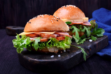 Sandwich with arugula salad, brisket and cheese on a black board