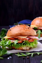Sandwich with arugula salad, brisket and cheese on a black board