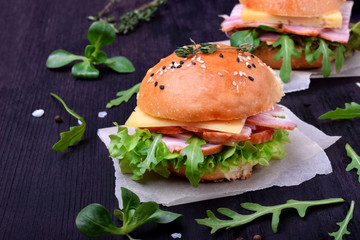 Sandwich with arugula salad, brisket and cheese on a black board