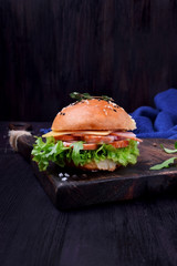 Sandwich with arugula salad, brisket and cheese on a black board
