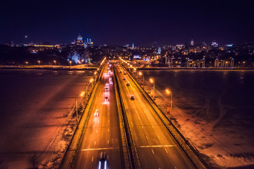 Fototapeta na wymiar Illuminated bridge with car traffic on night city background, aerial view