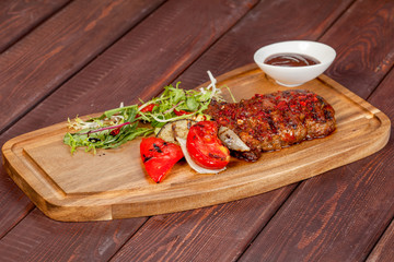  juicy, fried, tender steak with vegetables and sauces on a special stand