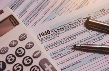 Tax season. calculator, pen on 1040 tax form background
