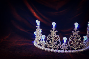 photo of gold crown over gothic dark silk background. Medieval period concept.