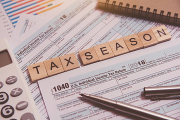 Fototapeta premium Tax season with wooden alphabet blocks, calculator, pen on 1040 tax form background