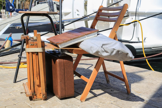 Touristenattraktion im Hafen von Saint-Tropez: Staffelei, Stuhl und Koffer eines Malers von Portraits und mediterranen Landschaften