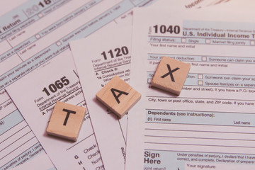 Tax with wooden alphabet blocks, pen on US tax form backgrounda