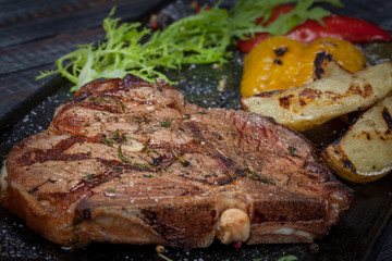  juicy, fried, tender steak with vegetables and sauces on a special stand