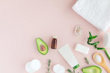 Obraz na płótnie Canvas Flatlay and top view of avocado, avocado oil, white towel, jar of cream, green leaves and bamboom avocado on pastel pink background. Products for spa beauty treatment