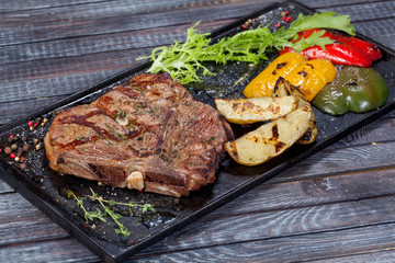  juicy, fried, tender steak with vegetables and sauces on a special stand