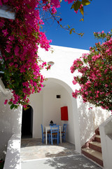 Building of hotel in traditional Greek style and Bougainvillea flowers, Santorini island, Greece
