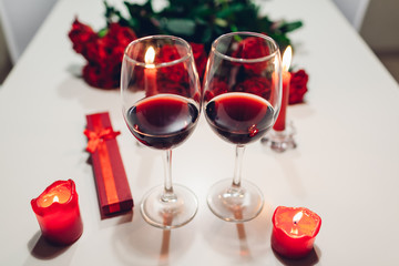 Celebrating Valentine's Day with wine, candles, roses and gift box at home. Romantic atmosphere for lovers