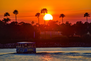 Orlando, Florida. January 11, 2019 Water taxi sailing on illuminated lake on colorful sunset at...