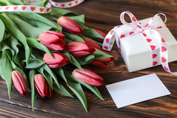 Bouquet of red tulips and gift on the wooden background, Valentines Day concept.