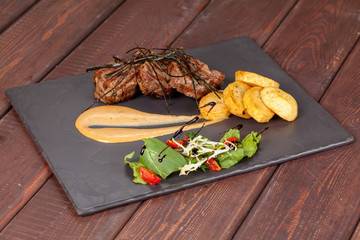  juicy, fried, tender steak with vegetables and sauces on a special stand