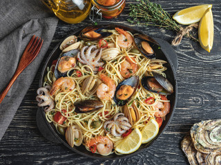 Cooked pasta with clams, shrimps, baby octopus, mussels tomato on a frying pan , spaghetti. Close up