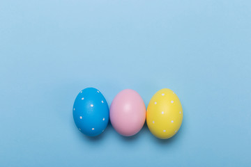 Colorfull easter eggs in nest on blue pastel color background with space.