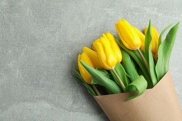 Beautiful bouquet of yellow tulips on grey background, top view. Space for text