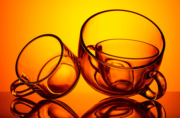 Round-shaped empty glass cups are photographed against the light on an orange background. - 248518978