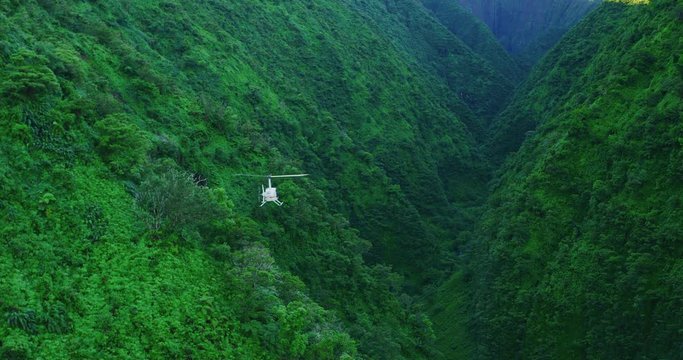 Aerial shot of helicopter flying in lush green valley, slow motion epic helicopter flying in valley