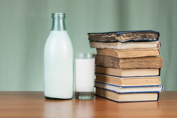 A bottle of milk and glass mug of milk with light green background