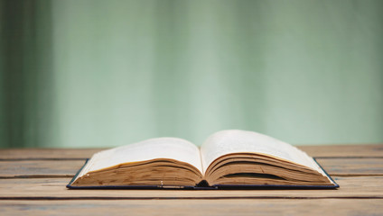 Opened book on the table - ancient knowledge - brown background