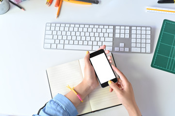 Mockup smartphone on woman hands using on office workspace.